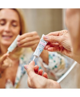 Donna allo specchio applica sul dito il siero contorno occhi